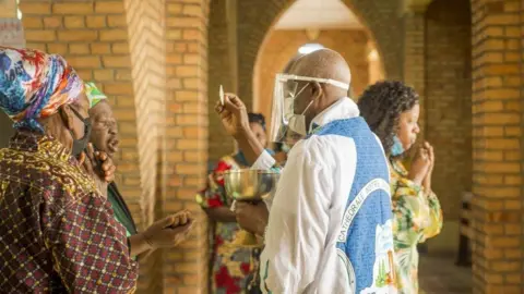 Getty Images A priest administers the Holy Communion during the service at the Notre Dame du Congo cathedral in Kinshasa on August 16, 2020