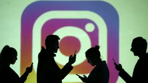 Reuters Silhouettes of mobile users are seen next to a screen projection of Instagram logo in this picture illustration taken March 28, 2018.