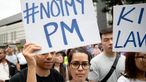 Getty Images Demonstrators hold placards during a protest