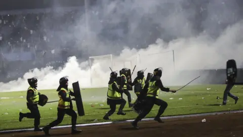 EPA Police officers in riot gear, with shields and batons, run down the field