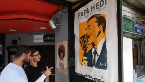 AFP Men looking at the post Papa Hedi - the man behind the microphone in Tunis, Tunisia - Tuesday 23 October 2018