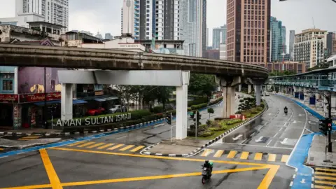 Getty Images A food delivery rider is seen riding along an empty street in downtown Kuala Lumpur. Malaysia government starts to further tighten the movement control and imposes lockdown in state of Selangor and parts of Kuala Lumpur.