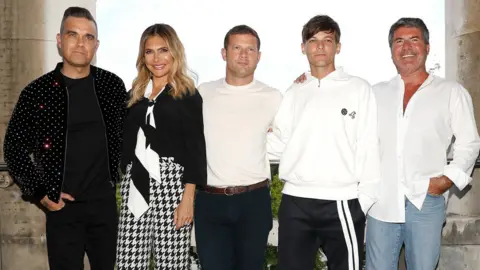 Getty Images L to R: Robbie Williams, Ayda Field, Dermot O'Leary, Louis Tomlinson and Simon Cowell