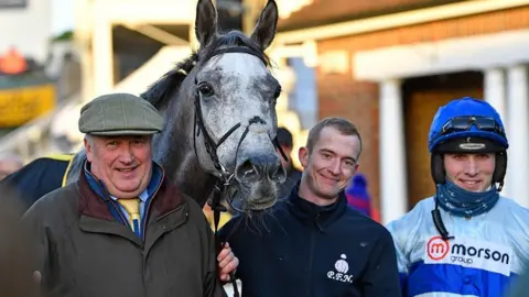 Tracy Roberts  Kirkby (centre) pictured with trainer Paul Nicholls (left) and jockey Harry Cobden (right)