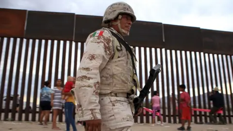 AFP A Mexican soldier walks past children playing at the border