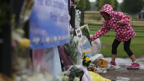 Getty Images A girl leaves flowers at the gates of the palace