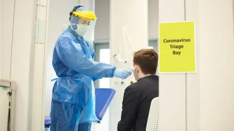 Getty Images A nurse in protective wear taking a temperature