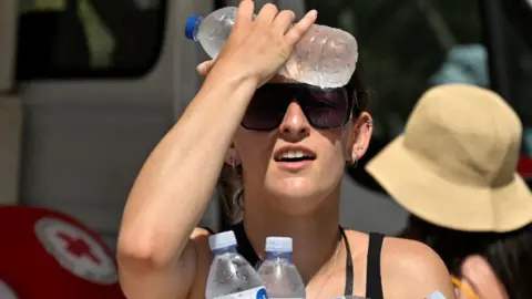 Getty Images A woman cools off with bottled water in Athens, Greece. Photo: 20 July 2023