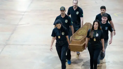 Getty Images Brazilian police officers transport the casket with human remains found found in the remote Amazon rainforest. Photo: 16 June 2022