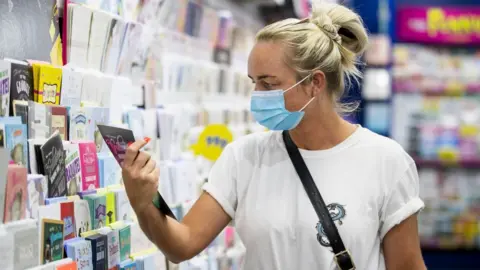 PA Media Maria Murtagh shopping in the Card Factory in Belfast while wearing a face mask as face coverings are now compulsory for shoppers in Northern Ireland.