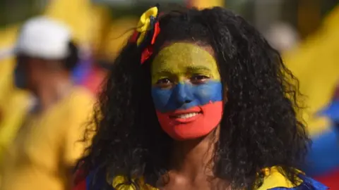 EPA Woman with the Colombian flag painted on her face takes part in protests against the tax reform, while commemorating International Workers' Day, in Cali, Colombia, 01 May 2021