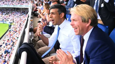 Getty Images Rishi Sunak watching a cricket match with Charles Banner KC