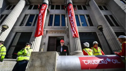 Courtesy Greenpeace Greenpeace activists scaled two entrance pillars to drop banners at the Canadian High Commission