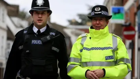 PA a police Chief Constable walks alongside a police officer