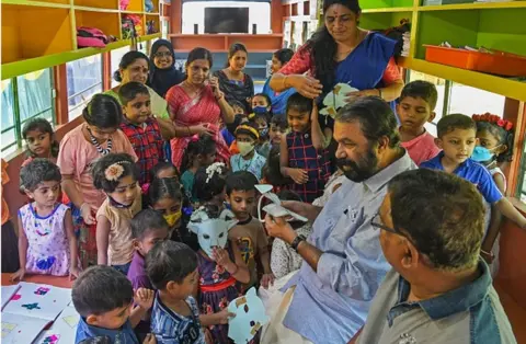 Getty Images Kerala minister for general education V Sivankutty (2R) with students inside a re-modified low-floor old defunct public transport bus transformed into a classroom for pre-nursery school children through an initiative 'Education on Wheels' taken by the state government at Thiruvananthapuram on June 13, 2022