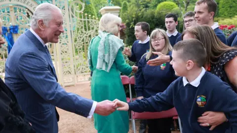 Reuters King Charles and Queen Camilla greeting school children at visit to a newly-created Coronation Garden in Newtownabbey,