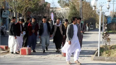 AFP Male students arrive at Herat University after it reopened on March 6, 2023.