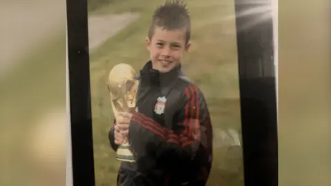 Family photo Neco Williams as a boy, holding a replica World Cup