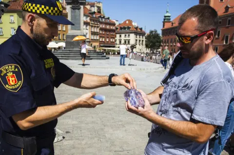 Getty Images The city guard in Warsaw gives water to citizens.