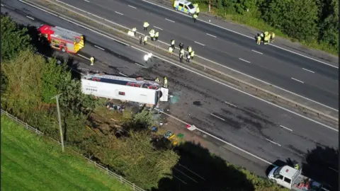 PA Media Emergency services at the scene of a coach crash on the M53 motorway