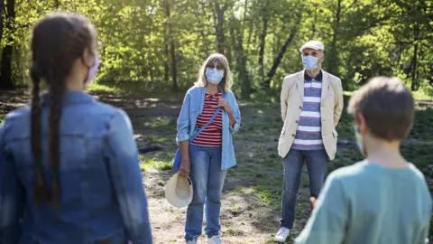 Getty Images Adults wearing masks meeting children outdoors