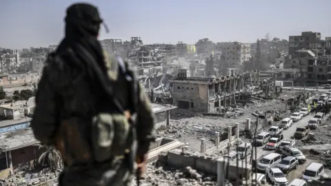 Getty Images A fighter of the Syrian Democratic Forces stands guard on a rooftop in Raqqa after retaking the city from Islamic State