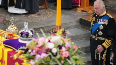 PA Media King Charles looks at the Queen's coffin during her funeral at Westminster Abbey