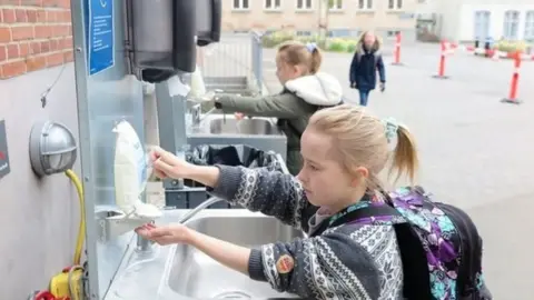 children washing hands at outdoor sinks