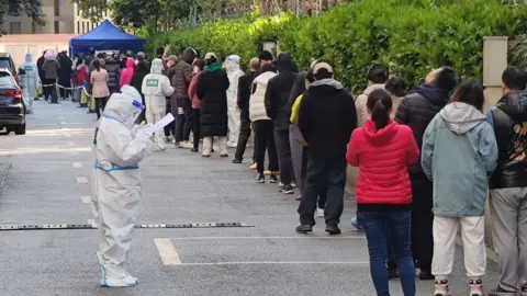 Getty Images Locals queue to get tested at a Covid clinic in Shanghai