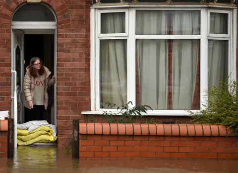 AFP A woman stands with sandbags outside her house