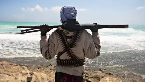 Photo made on January 7, 2010 shows an armed pirate keeping vigil along the coastline at Hobyo town, northeastern Somalia near where Greek cargo ship, MV Filitsa, is anchored since its capture by pirates November 10, 2009