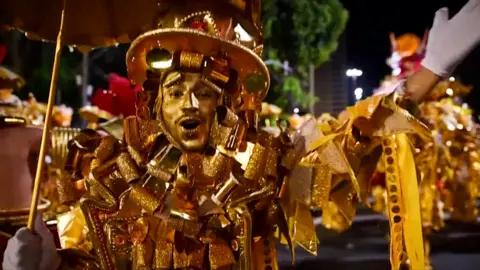 A man in a colourful, golden costume in Rio's carnival
