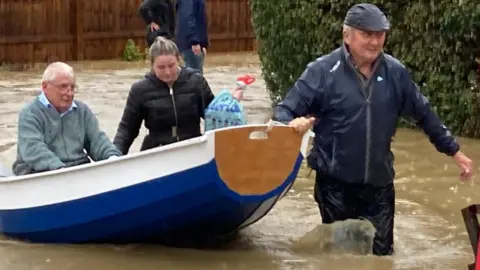 Mary Scott/PA Media Simon O'Brien pulling people to safety in his homemade paddleboat