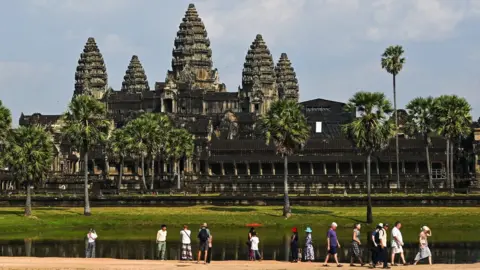 Getty Images Tourists walk in front of the Angkor Wat temple complex