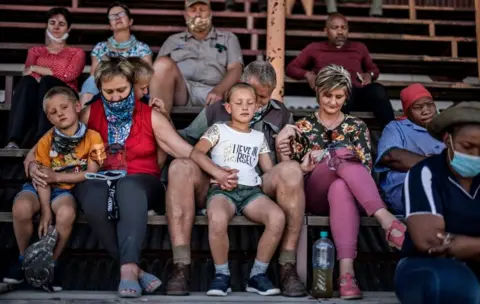 Getty Images A family hold hands as they collect themselves in prayer while taking part in a special mass prayer meeting in Senekal, on October 14, 2020.