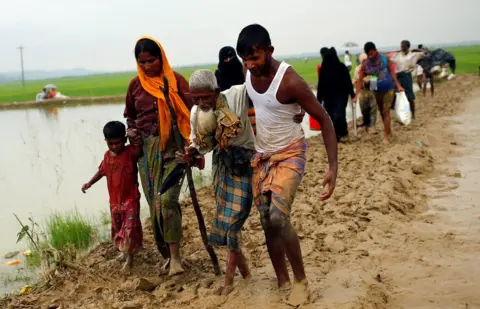 Reuters people helping an old man through mud