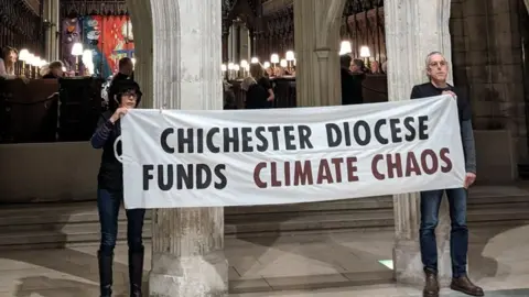 Christian Climate Action Climate protesters holding a banner that reads: Chichester Diocese funds climate chaos