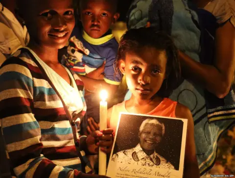 ALEXANDER JOE/afp People pose with a candle in memory of late South African former president Nelson Mandela outside his home in Johannesburg