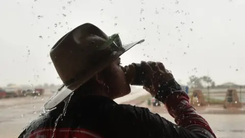 AFP An Australian woman drinking beer in the rain