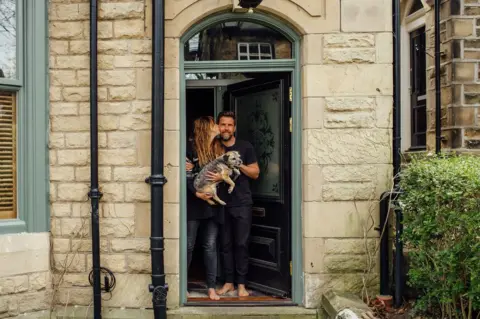 Ellie Grace Photography Doorstep portrait of Sally, Tim and Mini in Nether Edge