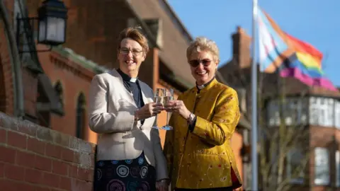 PA Media Catherine Bond (left) and Jane Pearce toasting after their blessing at St John the Baptist Church in Felixstowe, Suffolk