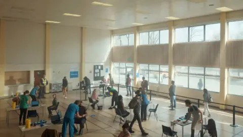 DHSC Queue at vaccination centre in government advert, "Every vaccination gives us hope"