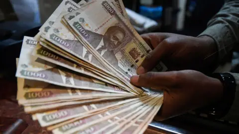 Getty Images A currency dealer counts Kenyan shillings at a money exchange bureau on September 19, 2018 in the Kenyan capital Nairobi.