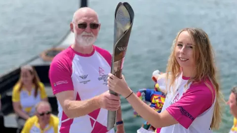 BBC Neil Kegg and Rossana Dale holding the Queen's baton