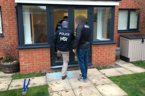 National Crime Agency Police entering a property as part of an investigation into a gang selling large quantities of ecstasy around the world on the dark web