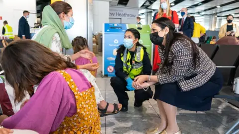 Getty Images Home Secretary Priti Patel meets an Afghan refugee