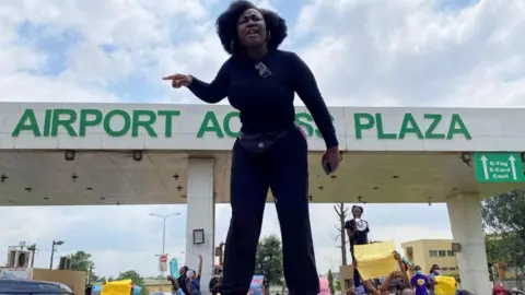 Reuters A demonstrator stands atop a vehicle and shouts slogans as others carry banners while blocking a road leading to the airport, during a protest over alleged police brutality, in Lagos, Nigeria October 12, 2020.