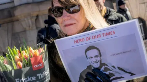 EMIL NICOLAI HELMS/Ritzau Scanpix/AFP Protestors hold a picture of late Kremlin opposition leader Alexei Navalny reading 'hero of our times' in front of the Russian embassy in Copenhagen on March 17, 2024 during a presidential election in Russia