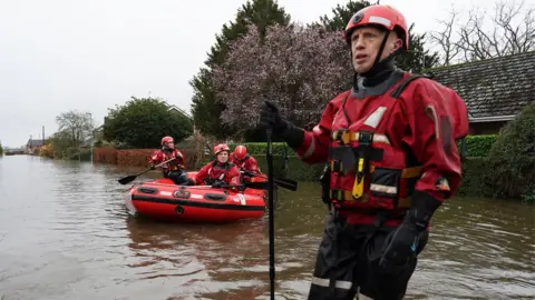 Getty Images Humberside Fire and Rescue service search along a flooded street for residents after the River Aire bursts its banks