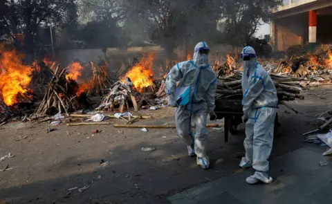 Adnan Abidi / Reuters Health workers carry wood for funeral pyres in New Delhi, India